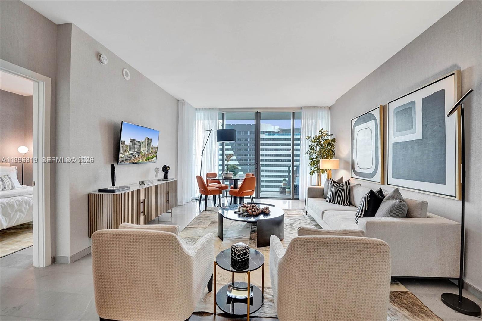 88 Southwest 7th Street, Unit 1408 Miami, FL 33130 - Photo 8 of 16 a living room with furniture a flat screen tv and a large window