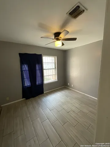 an empty room with windows and fan