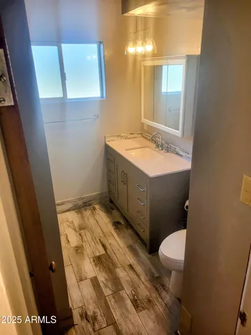 a bathroom with a granite countertop toilet sink and mirror