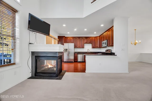 a open kitchen that has a fireplace a flat screen tv a island and stainless steel appliances