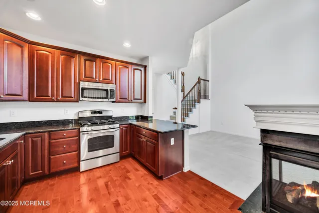 a kitchen with stainless steel appliances granite countertop a stove top oven a sink dishwasher and a microwave oven with large trees