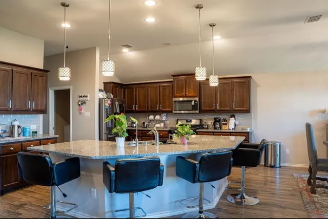 a kitchen with granite countertop a refrigerator dining table and chairs