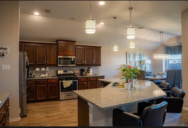 a kitchen with stainless steel appliances granite countertop a sink a stove a refrigerator and island