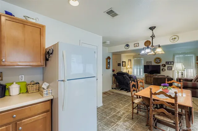 a kitchen with a refrigerator a stove top oven a dining table and chairs