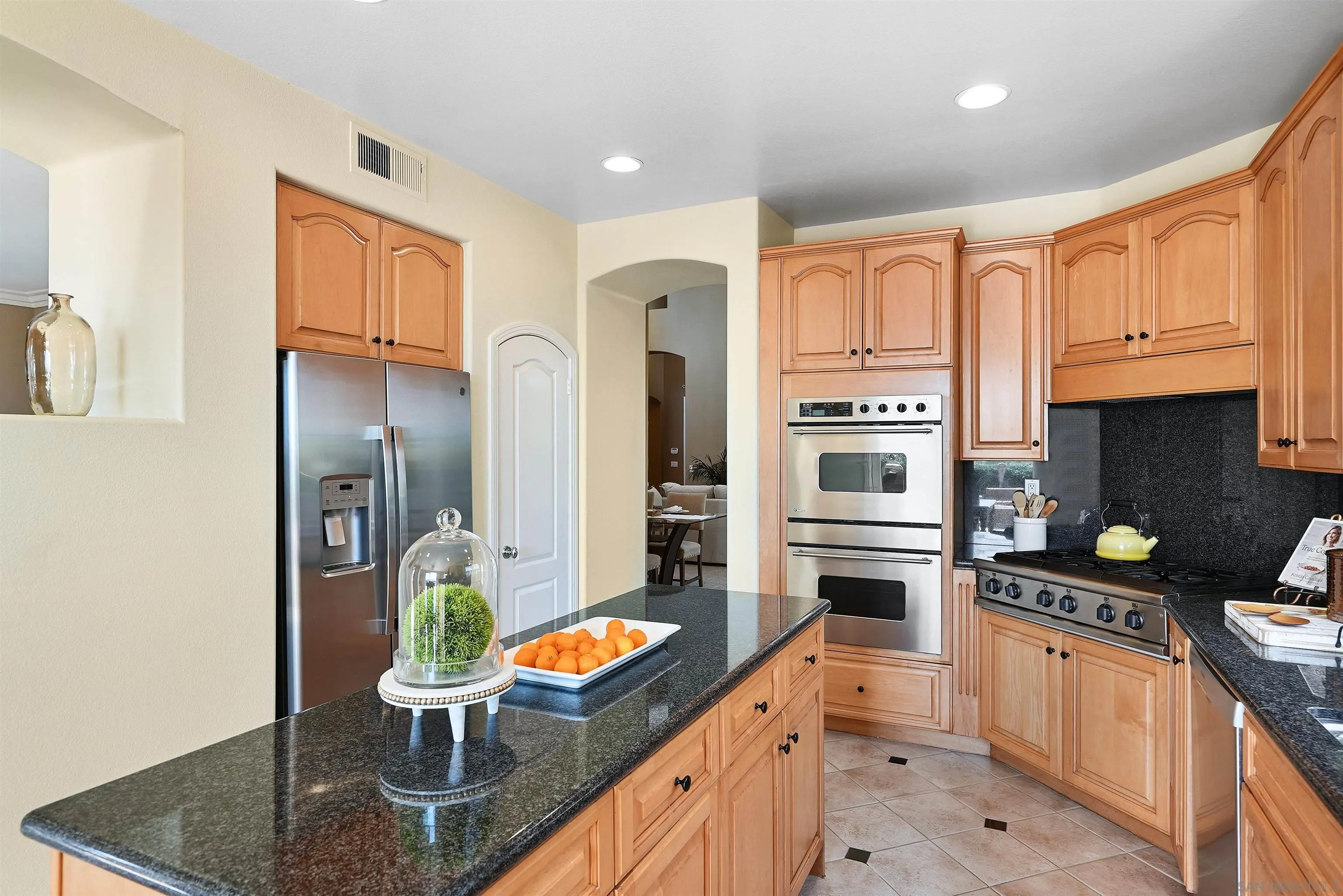 7539 Reeve Road Carlsbad, CA 92011 - Photo 10 of 30 a kitchen with stainless steel appliances granite countertop a refrigerator a stove and a sink with wooden floor
