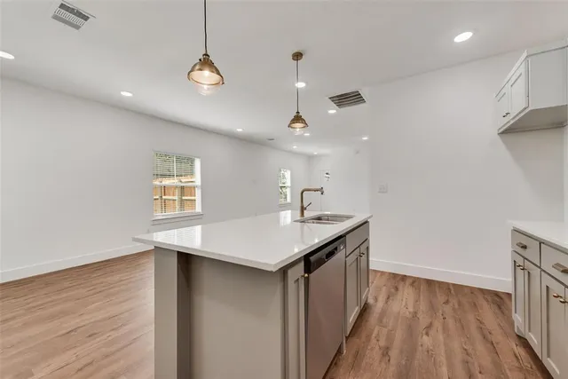a kitchen with a sink stainless steel appliances and wooden floor