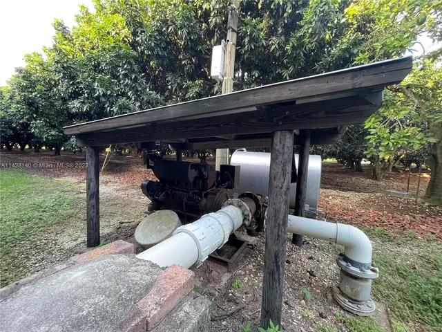 a view of a backyard with table and chairs potted plants and large trees