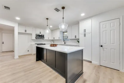 a kitchen with kitchen island a sink stainless steel appliances and cabinets