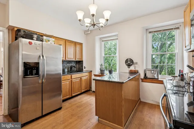 a kitchen with stainless steel appliances granite countertop a refrigerator a sink dishwasher a stove and white countertops with wooden floor