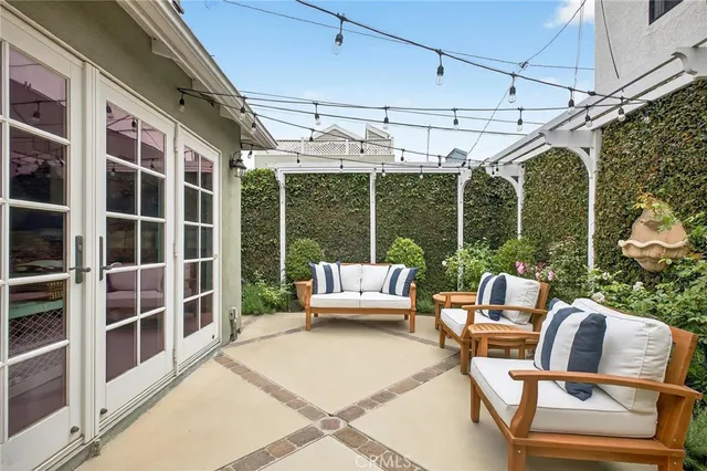 a view of a patio with couches chairs potted plants and floor to ceiling window