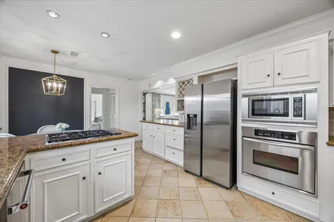 a kitchen with stainless steel appliances granite countertop a refrigerator a stove and white cabinets