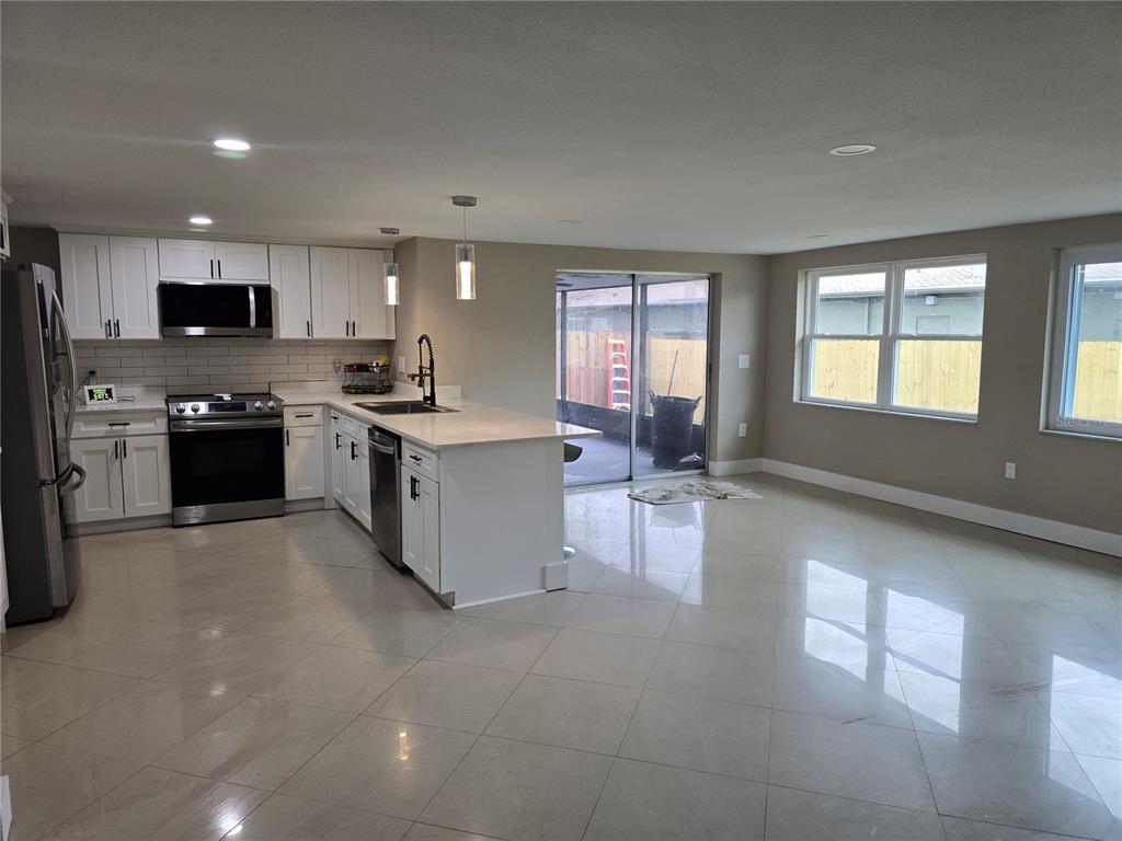 5813 Chapman Drive New Port Richey, FL 34652 - Photo 15 of 33 a large kitchen with stainless steel appliances granite countertop a stove top oven a sink dishwasher and white cabinets with wooden floor