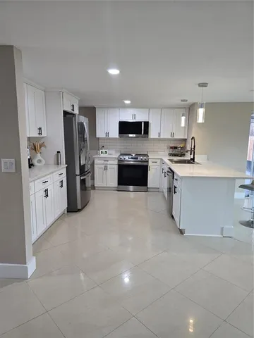 a large kitchen with stainless steel appliances a refrigerator sink and cabinets