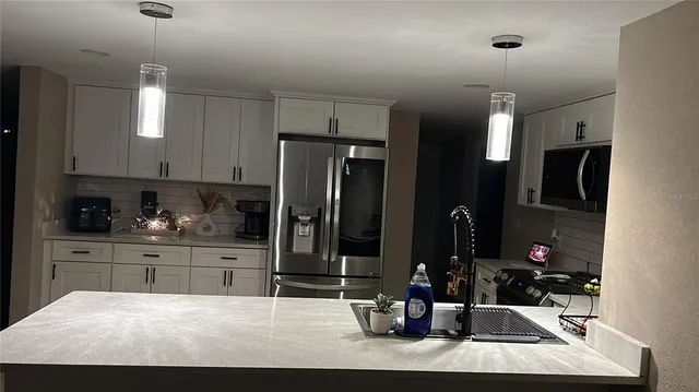 a kitchen with stainless steel appliances kitchen island granite countertop a refrigerator and cabinets