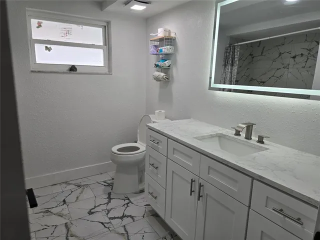 a bathroom with a granite countertop toilet a sink and mirror