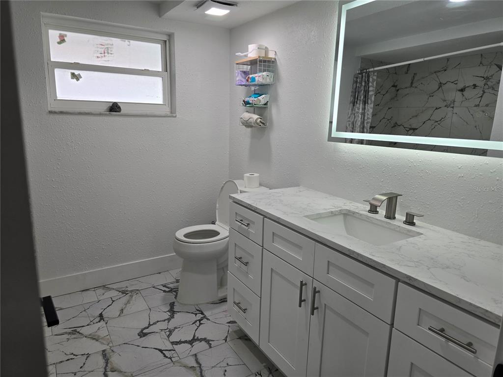 5813 Chapman Drive New Port Richey, FL 34652 - Photo 25 of 33 a bathroom with a granite countertop toilet a sink and mirror