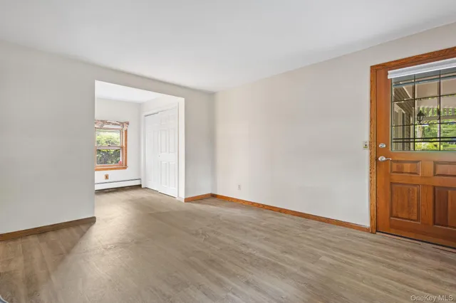 a view of an empty room with a window and wooden floor