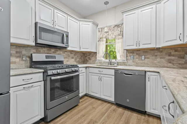 a kitchen with granite countertop white cabinets stainless steel appliances and sink