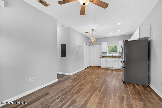 a kitchen with a refrigerator stove and white cabinets with wooden floor