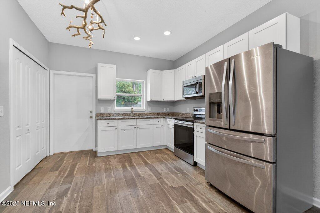 932 Puryear Street St. Augustine, FL 32084 - Photo 7 of 29 a kitchen with a refrigerator stove and white cabinets with wooden floor
