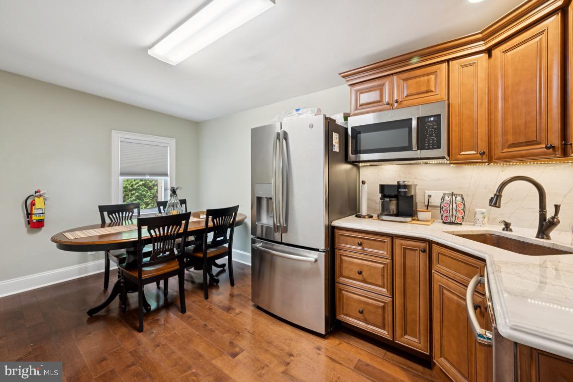 1526 Haddonfield-Berlin Road Cherry Hill, NJ 08003 - Photo 14 of 24 a kitchen with stainless steel appliances granite countertop a stove a refrigerator a sink dishwasher a dining table and chairs with wooden floor