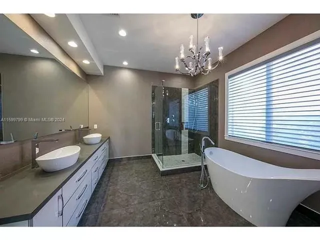 a spacious bathroom with a granite countertop sink a large mirror and a bathtub