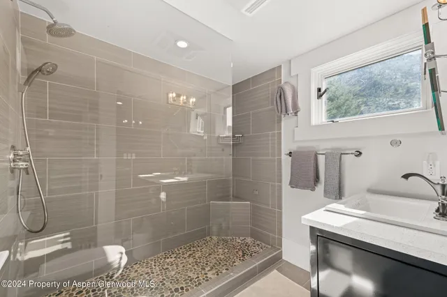 a bathroom with a granite countertop sink a toilet and shower