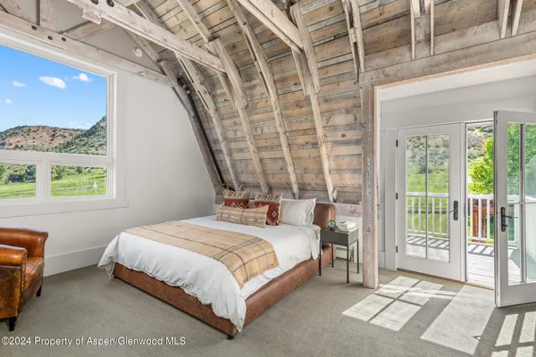 a bedroom with a bed lamp and a large window with the garden view