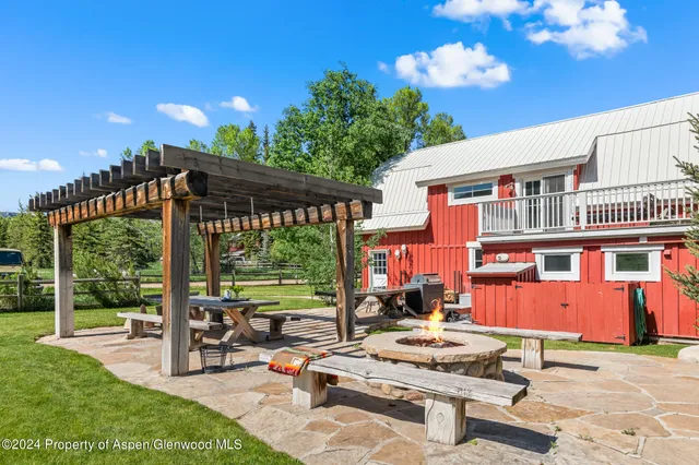a view of a patio with table and chairs potted plants and large tree