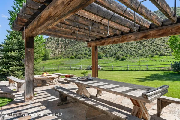 a view of a patio with table and chairs under an umbrella with a big yard