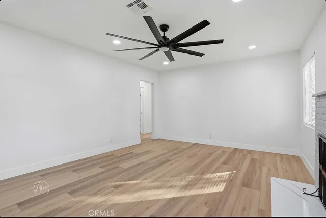 a view of a room with a ceiling fan and wooden floor