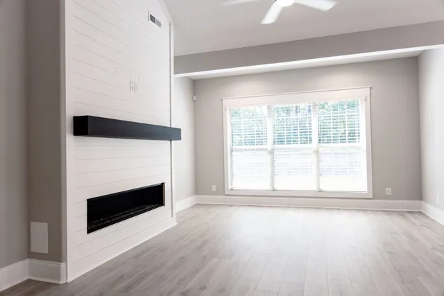 an empty room with wooden floor fireplace and windows