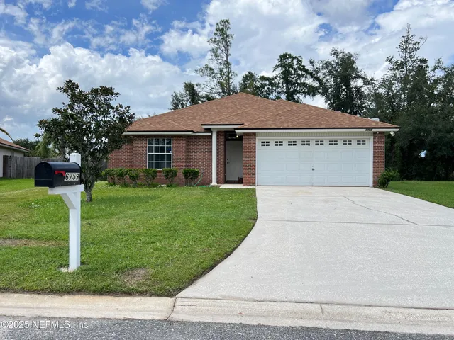 a view of a house with a yard plants and a large tree