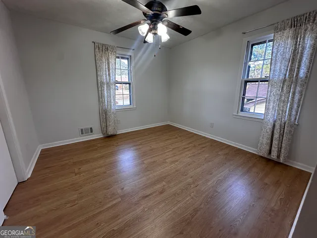 a view of an empty room with wooden floor and a window