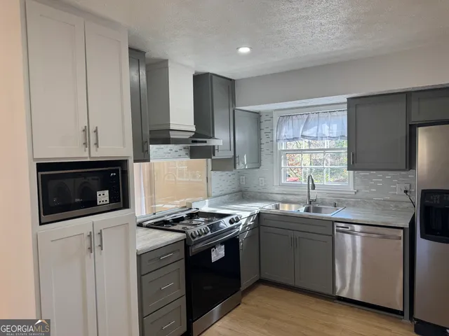 a kitchen with stainless steel appliances granite countertop a stove a sink and a microwave