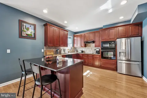 a kitchen with stainless steel appliances granite countertop a refrigerator a stove a sink a dining table and chairs