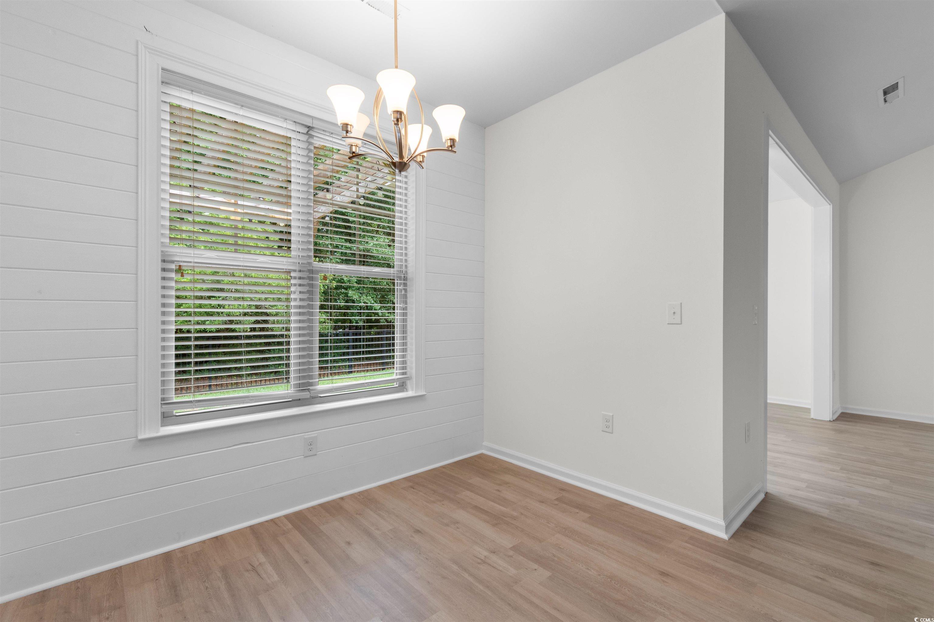 124 Shady Arbor Loop Longs, SC 29568 - Photo 11 of 40 Spare room featuring light wood-type flooring, a chandelier, and wood walls