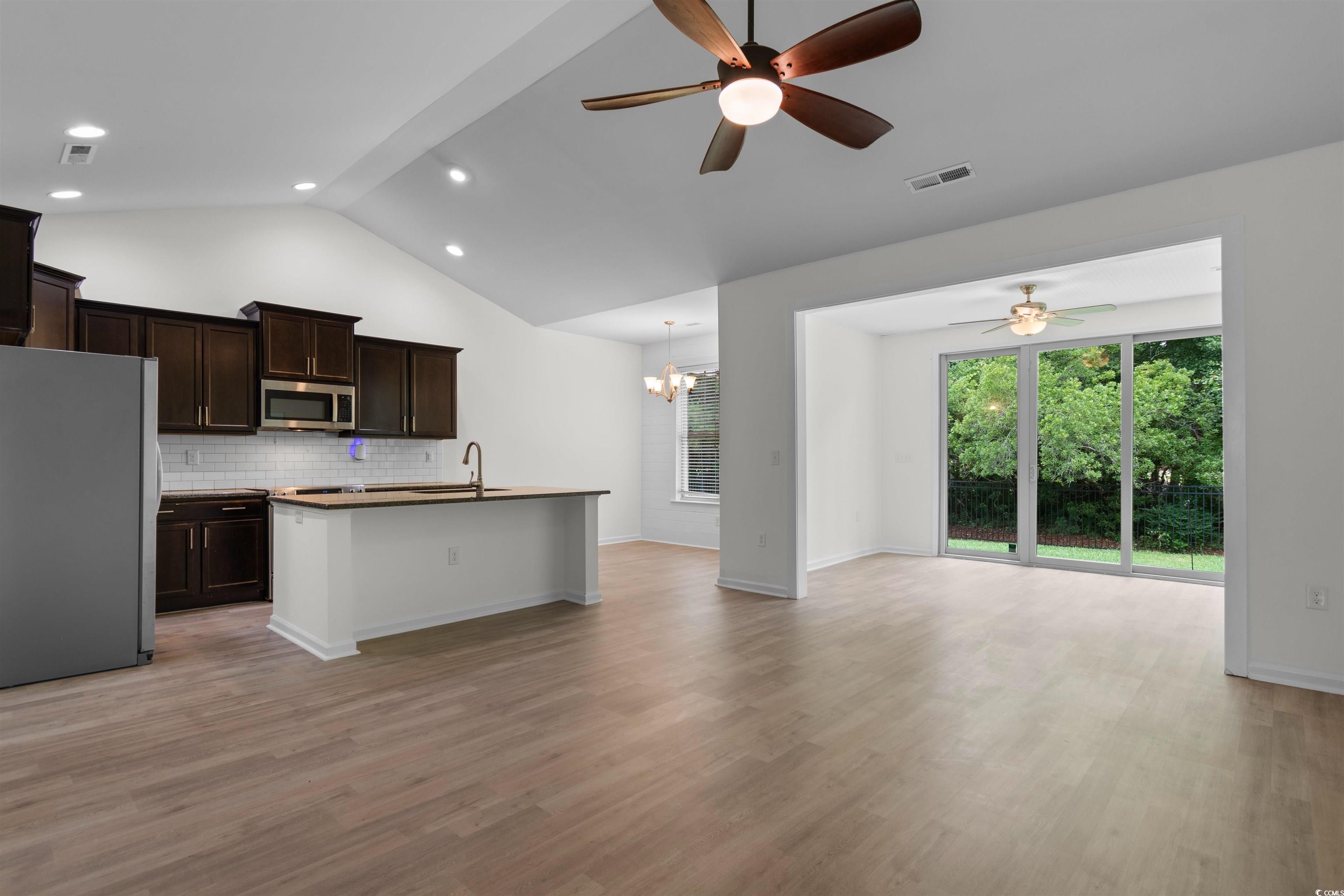 124 Shady Arbor Loop Longs, SC 29568 - Photo 39 of 40 Kitchen with appliances with stainless steel finishes, open floor plan, ceiling fan, vaulted ceiling, and light wood-style flooring