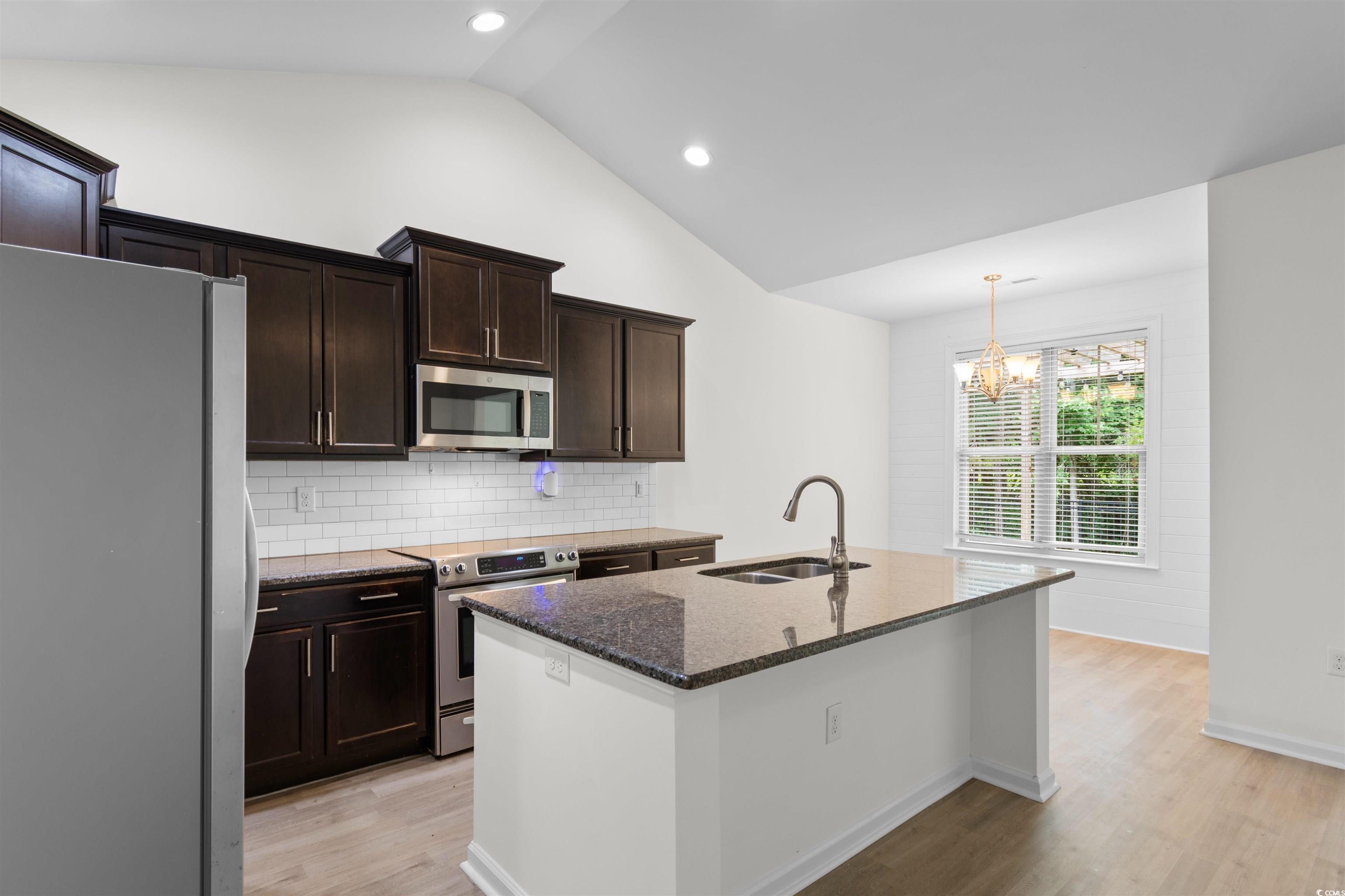 124 Shady Arbor Loop Longs, SC 29568 - Photo 3 of 40 Kitchen with stainless steel appliances, vaulted ceiling, dark stone countertops, light wood-type flooring, and backsplash
