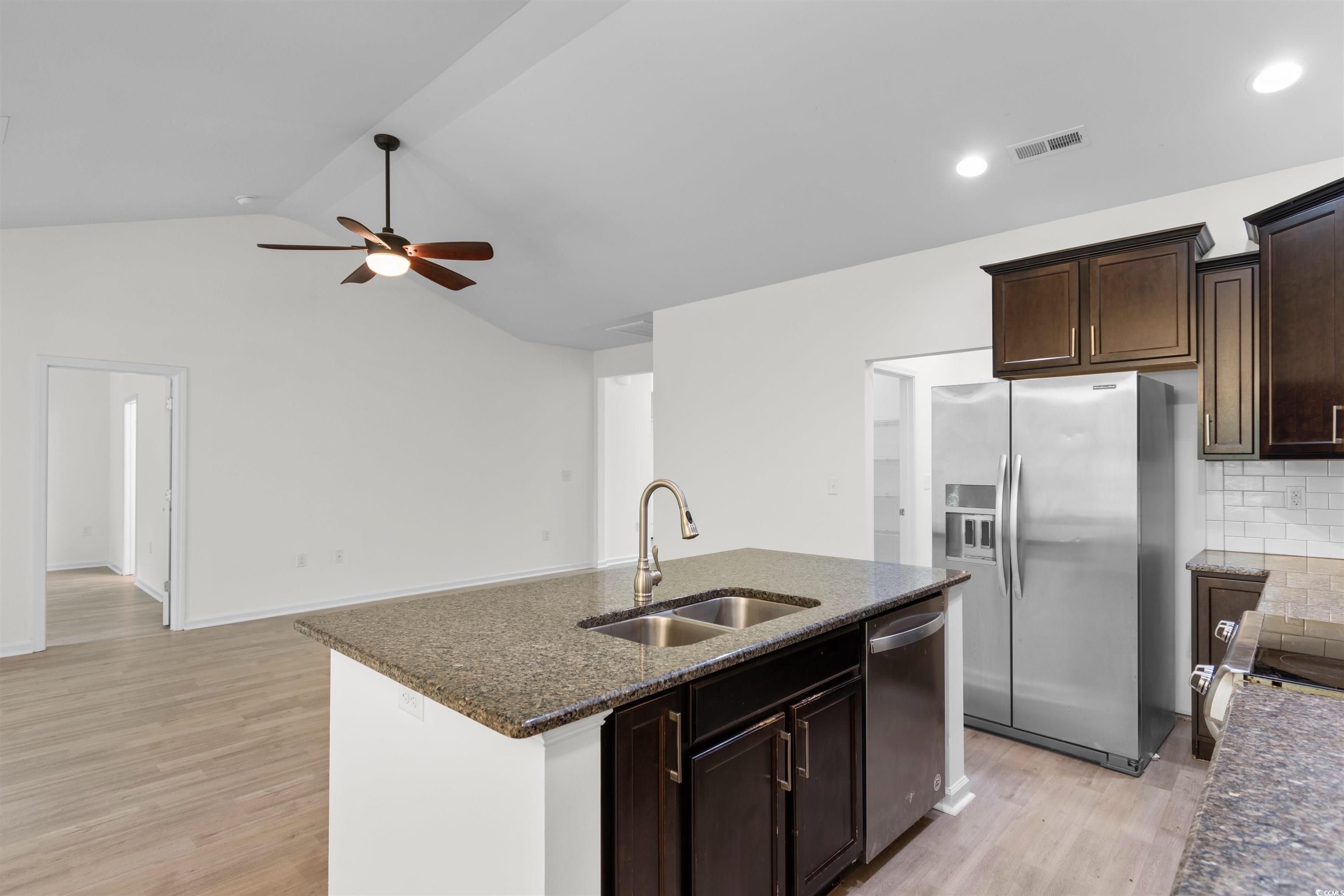 124 Shady Arbor Loop Longs, SC 29568 - Photo 7 of 40 Kitchen featuring appliances with stainless steel finishes, a ceiling fan, light wood-style flooring, dark stone countertops, and vaulted ceiling
