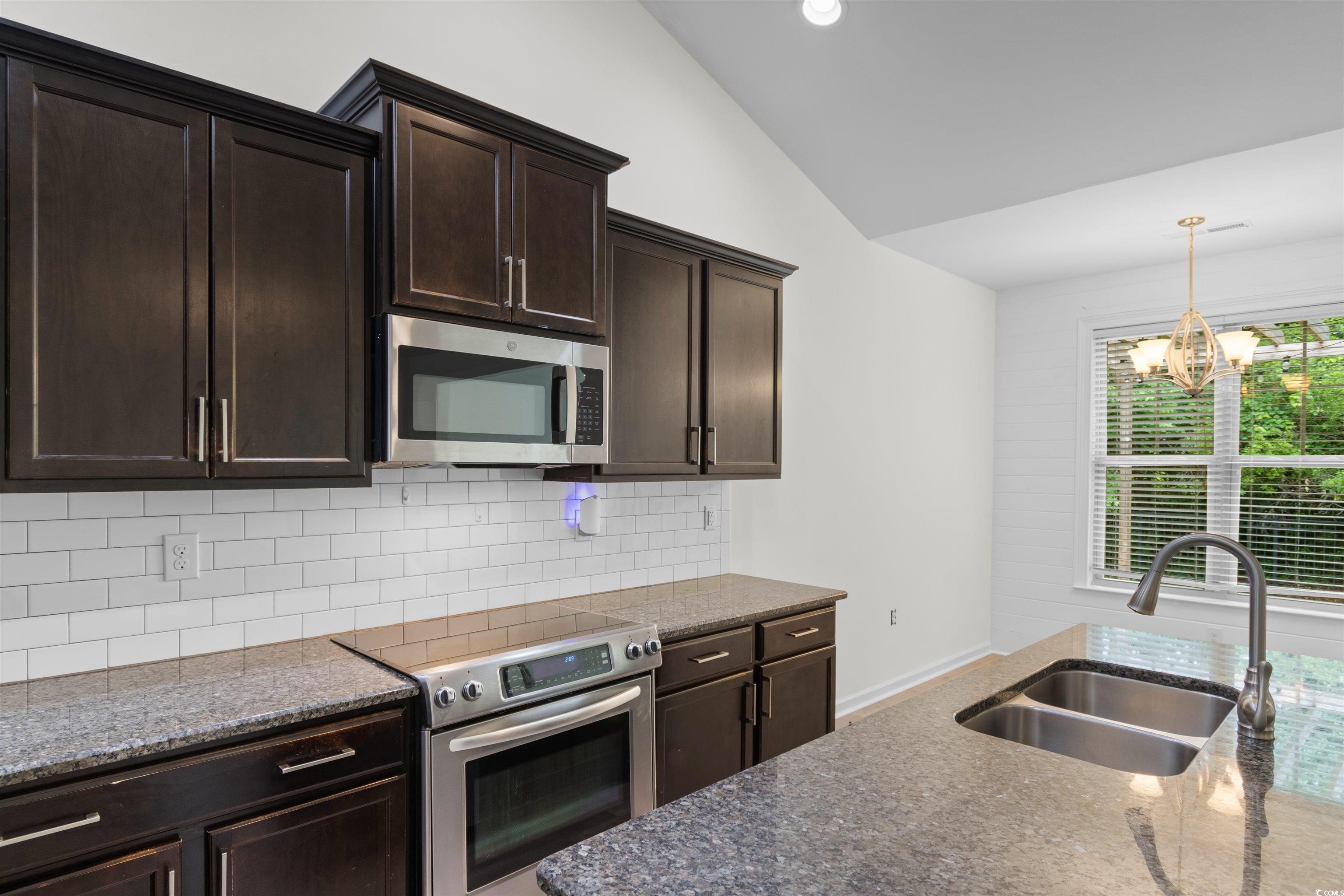 124 Shady Arbor Loop Longs, SC 29568 - Photo 8 of 40 Kitchen featuring appliances with stainless steel finishes, vaulted ceiling, a chandelier, dark brown cabinets, and decorative backsplash