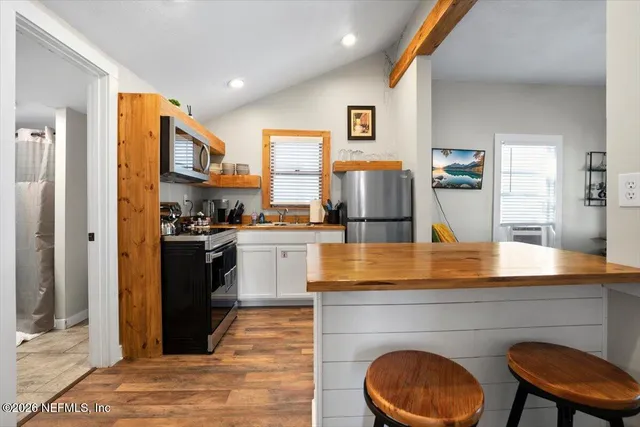 a large kitchen with stainless steel appliances kitchen island granite countertop a refrigerator and a stove top oven