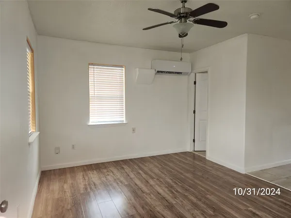 a view of a room with wooden floor and a ceiling fan