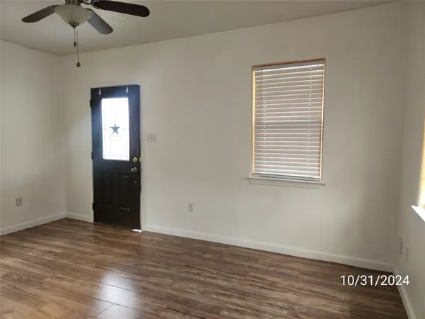 an empty room with wooden floor cabinet and windows