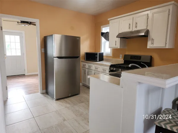a kitchen with stainless steel appliances granite countertop a refrigerator a stove and a sink