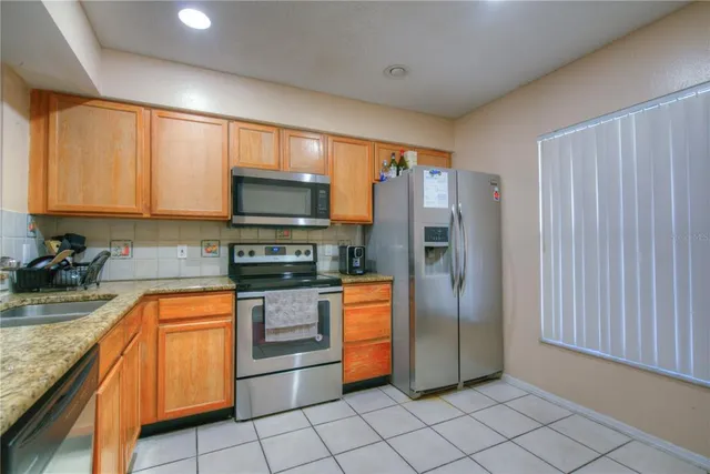 a kitchen with stainless steel appliances granite countertop a refrigerator and a stove top oven