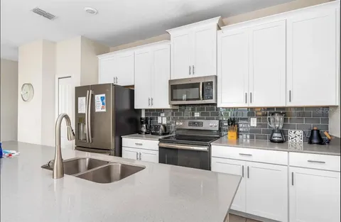 a kitchen with stainless steel appliances granite countertop a sink a stove and white cabinets