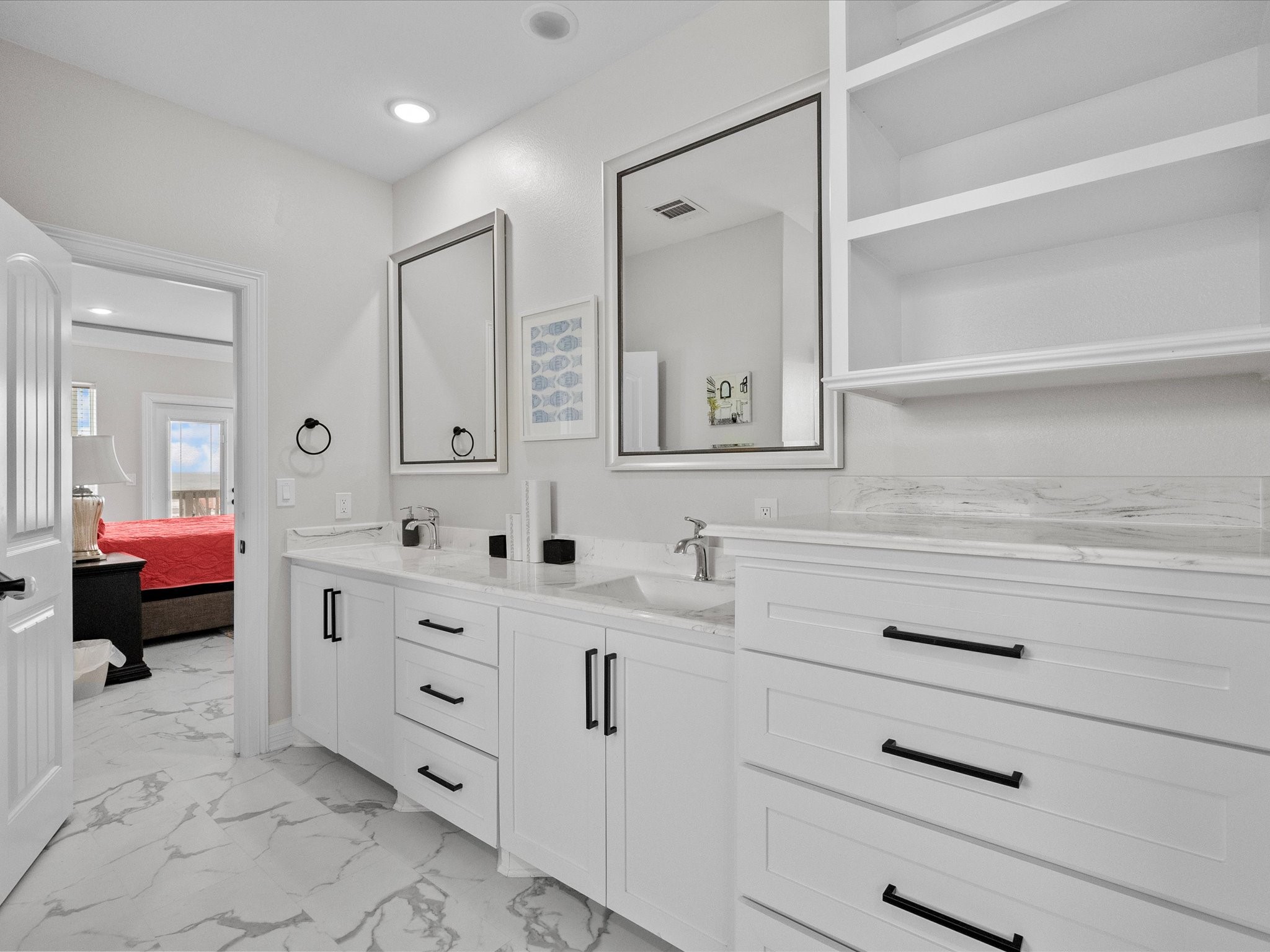 1018 Seashell Drive Surfside Beach, TX 77541 - Photo 45 of 49 Bright, modern bathroom with white cabinetry and marble countertops. Features dual sinks, ample storage, and stylish black hardware. Adjoins a bedroom with a view.