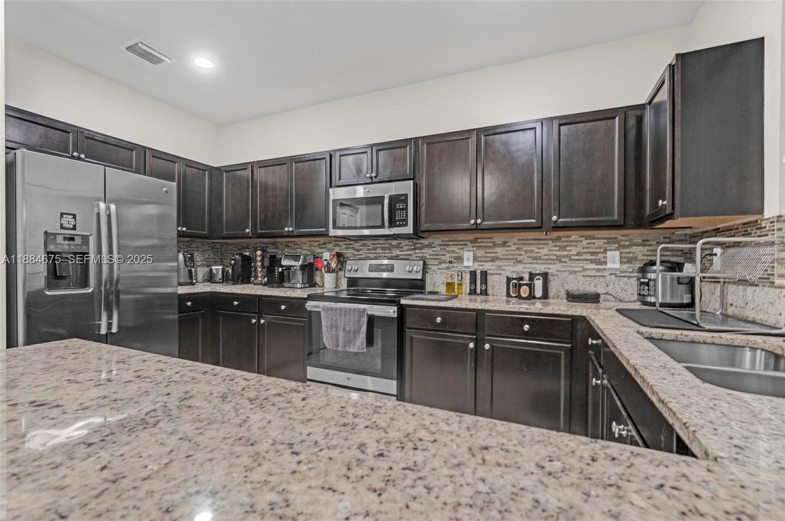 11413 Southwest 253rd Street, Unit 11413 Homestead, FL 33032 - Photo 24 of 44 a kitchen with kitchen island a sink stove and refrigerator