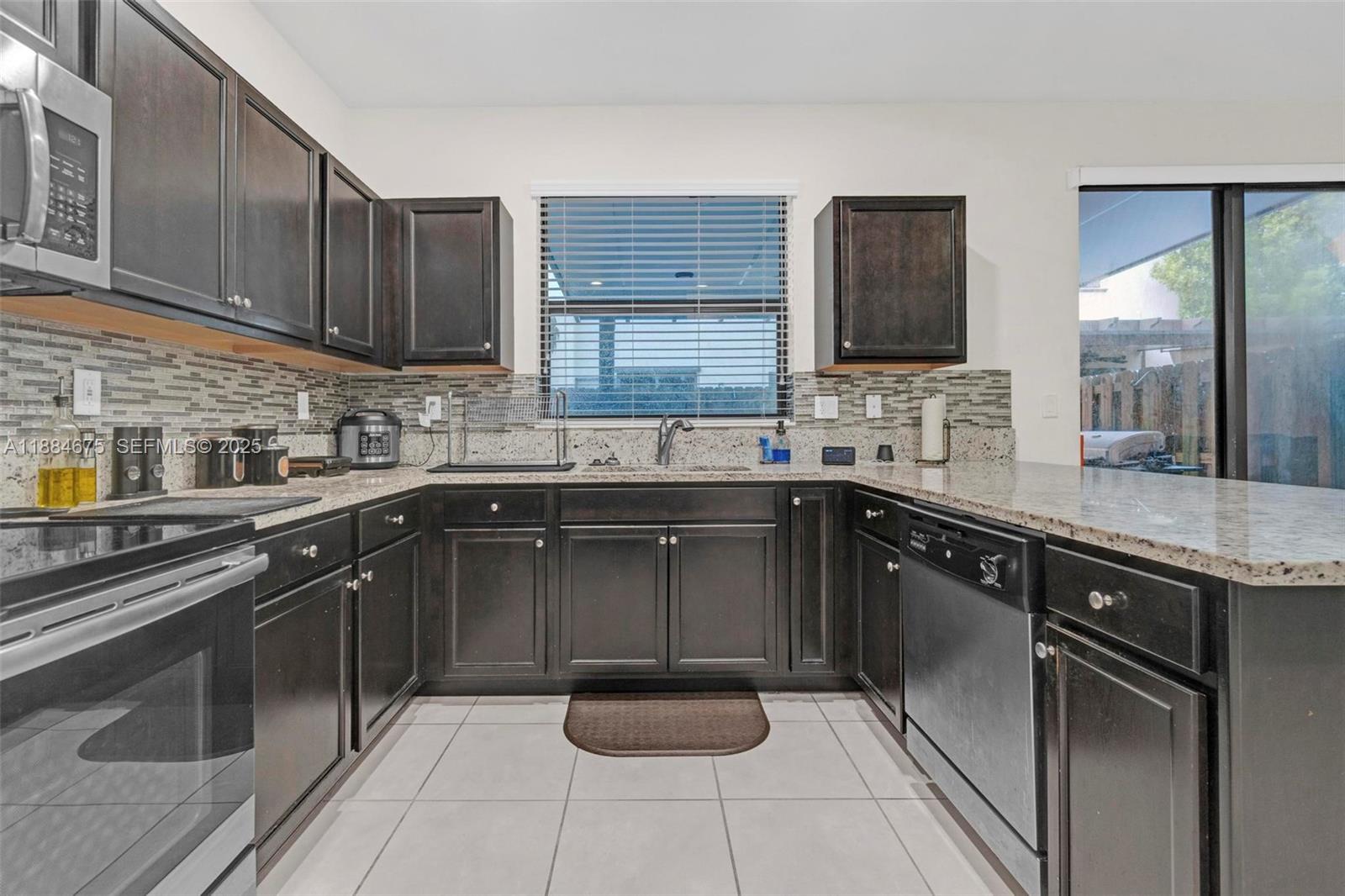 11413 Southwest 253rd Street, Unit 11413 Homestead, FL 33032 - Photo 6 of 44 a kitchen with a sink and a stove